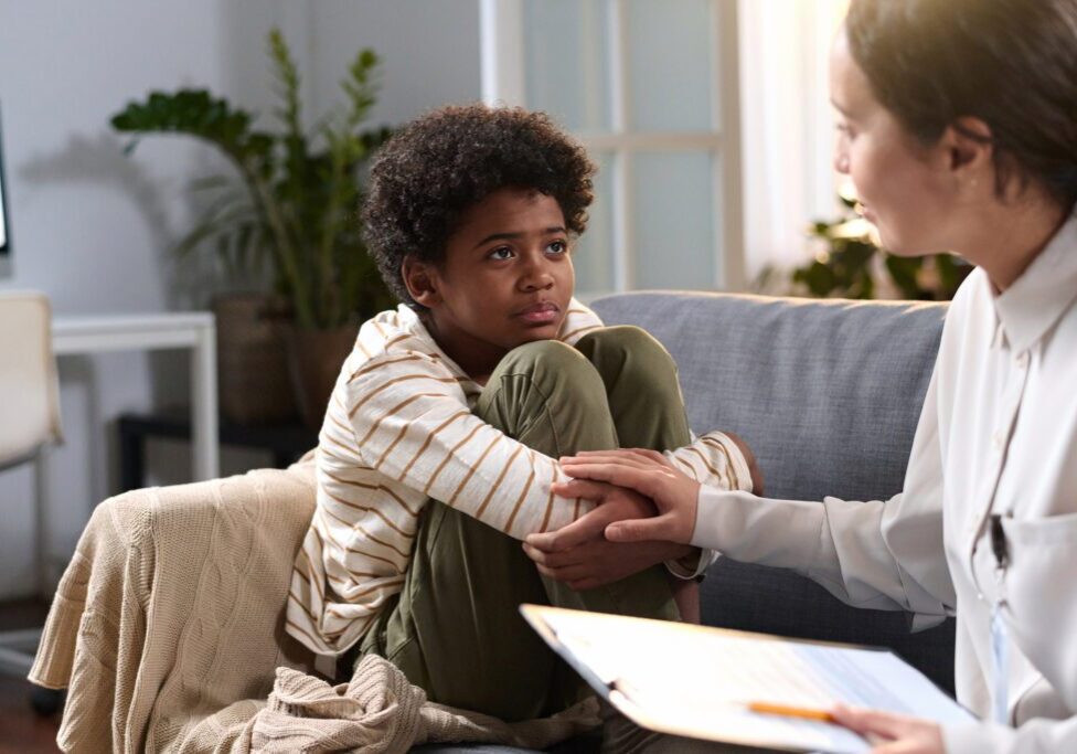 Child and adult talking on a couch.